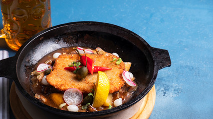 Chicken schnitzel on a frying pan with copy space.