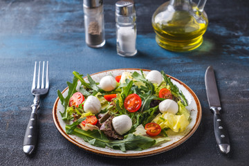 Diet salad with arugula, lettuce,  cherry tomatoes and mozzarella cheese.
