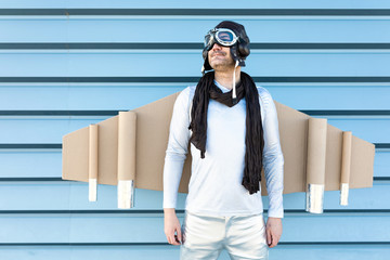 man in silver suit with glasses and aviator helmet and cardboard plane wings
