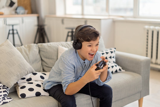 Brunette boy in headphone playing video game and crying