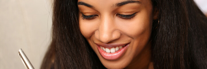 Fototapeta premium Smiling black woman write story in notebook