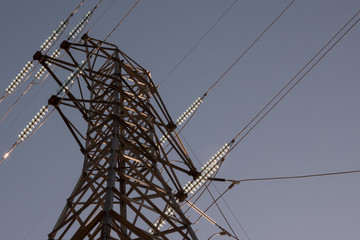 Electrical Transmission Line Tower with glass insulators glowing in the sun