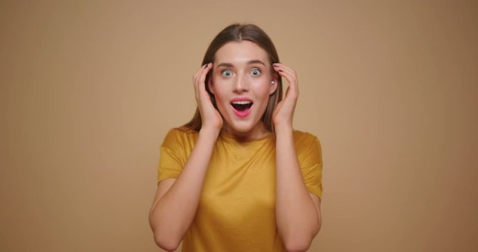 Young shocked surprised woman isolated over yellow background looking at camera.