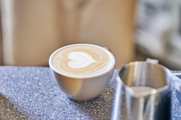mug with cappuccino and stewpan. drawing heart on coffee