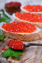 Sandwiches with bran bread, red caviar and butter on white wooden table