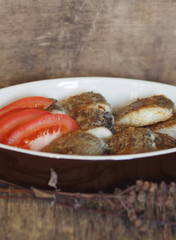 stew fried fish in a baking sheet on a wooden rustic table