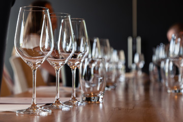 Closeup empty clear transparent crystal wine and water glasses standing on table in straight rows on wine tasting. Concept modern setting on background professional degustation with sommelier