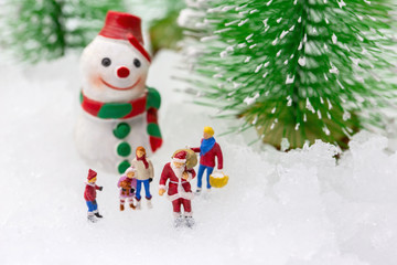 Happy snowman on snow with background of blurred Christmas pine. Miniature people in Christmas Theme.  