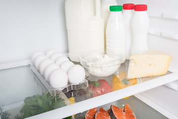 on the shelf in the refrigerator are dairy products and cheeses