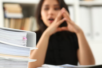 Tired and exhausted woman looks at documents propping up her head with her hands