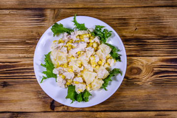 Festive salad with chicken breast, canned pineapple, cheese, sweet corn and mayonnaise on wooden table. Top view