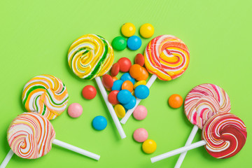 many multi-colored caramel candies on a stick lie on a green background