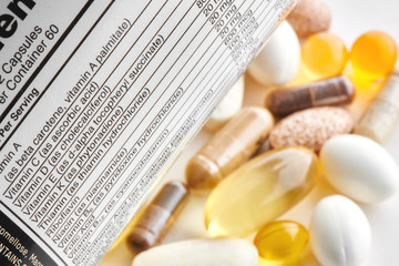 Close-up of a white label with supplements facts of a multivitamin complex, vitamin capsules, medicines and tablets