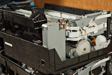 The printer is disassembled into parts. Broken, dirty and dusty printer. Service center for equipment repair. Refilling with ink and cleaning of printing equipment.