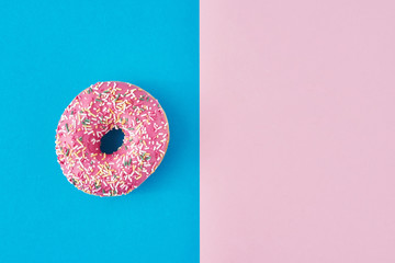 donut on a pastel pink and blue background. Minimalism creative food composition. Flat lay style