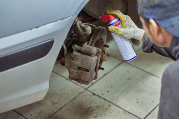 mechanic lubricates the car suspension parts of a car in service