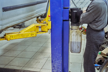 mechanic controls the lifting of a car on a lift in service