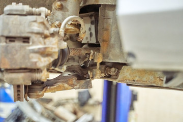 rusty parts of the front suspension of an old car lifted to a lift