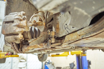 rusty parts of the front suspension of an old car lifted to a lift