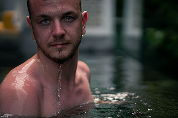 Portrait d'un jeune homme mouillé dans une piscine