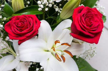 Bouquet of flowers close-up on a white background. Two red roses and a white lily.