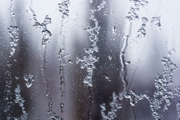 glass in the window covered with wet melting snow, close-up, macro photo