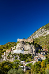 Fototapeta na wymiar A view of the ancient village of Cerro al Volturno, surrounded by green woods and mountains. The Pandone castle stands on top of the hill, on a rock spur. Isernia, Molise, Italy.