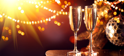 Holiday Champagne Flute over Golden glow background. Christmas and New Year celebration. Two Flutes...