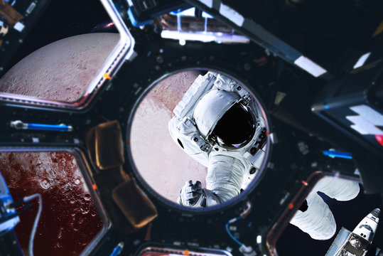 Astronaut near Planet Pluto of Solar system in space with far galaxy on the background. View from space station illuminator. Spaccewalk concept. Elements of this image were furnished by NASA 