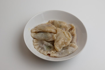 Boiled dumplings with butter in a white plate on a white background