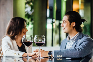 Young happy couple at romantic date, glass of red wine at restaurant, celebrating valentine day.