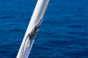 Sea knot on a white flagpole on sail boat on water surface background with lot of little waves