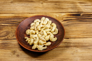 Ceramic plate with raw cashew nuts on a wooden table
