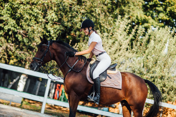 Young rider woman on bay horse performing advansed test on dressage competition.