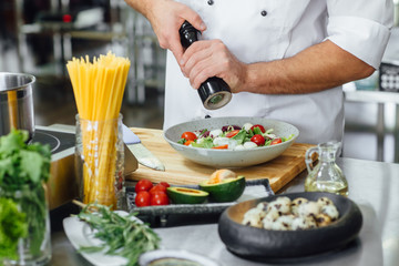 Chef finishing her plate and almost ready to serve at the table. Only hands. Finally dish dressing.