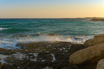 Rocky coast of the turquoise sea at sunset