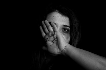 Stopping violence against women, Woman covering her face in fear of domestic violence, Dark tone