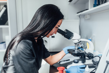 Chemical research looking. Cheerful brunette girl wearing medical uniform while working with reagent. Close up photo. Medicine time.