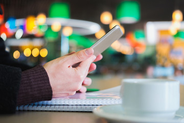 Human hands hold a tablet or e-book at a public place, close-up view. Using technology on the go at the shopping mall, airport or food courts