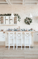 Interior light kitchen with christmas decor and tree. White kitchen in classic style. Christmas in the kitchen. Bright kitchen in white shades with Christmas.