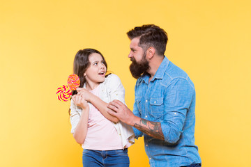 this is mine. my dessert only. candy shop. happy childhood. Daughter and dad eat candy. bearded hipster man is good father. little girl and dad hold colorful lollipop. summer vibes. happy family