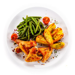 Fried chicken wings with baked potatoes and vegetable salad