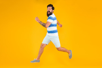Fototapeta na wymiar time to relax. active runner in move. Hurry up. Summer vacation. Man bearded hipster run yellow wall. Guy beard striped shirt. Freedom jump. Sale and discount. rush hour. lets go seasonal shopping