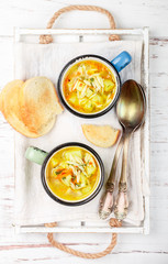 Minestrone. Chicken soup with potatoes, carrots and Orzo pasta in ceramic mugs on a wooden table. Minestrone. Mediterranean (Italian) cuisine. Selective focus