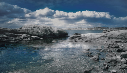 Blue tones of enclosed rock and bright white clouds in the distant horizon in Newport, Rhode Island...