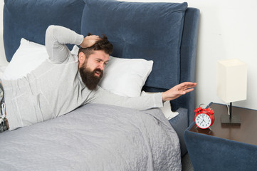 Fototapeta premium hate noise of alarm clock. having terrible headache. Man at home. Health care concept. need more relax in bed. stressed and unhappy man. bearded man hipster want to sleep. early morning awakening