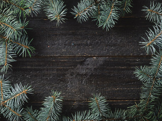 Winter and Christmas background. Christmas tree branches on a dark wooden background with copyspace in the center