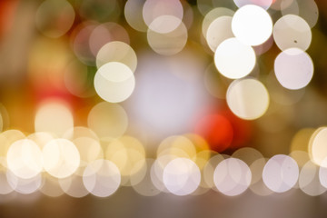Fototapeta premium Blurry bokeh warm white light lights shining near the blurry Christmas decor and New Year tree. Background concept for Happy New Year greetings and advertising. Place for text