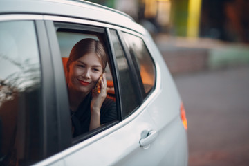 Young woman sitting in back seat of car vehicle with mobile phone. Taxi concept.