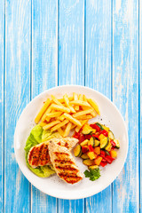 Grilled chicken breast with french fries and vegetables